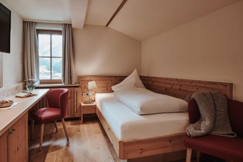 a bedroom with a bed and a desk and a window at Hotel Austria Lech in Lech am Arlberg