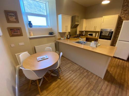 a kitchen with a wooden table and a wooden floor at Roy Place Gdn Apartment in Campbeltown