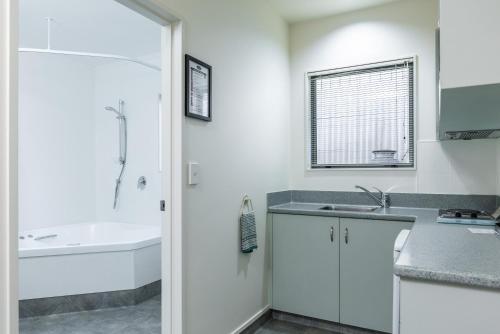 a white bathroom with a sink and a bath tub at Jasmine Court Motel in Picton