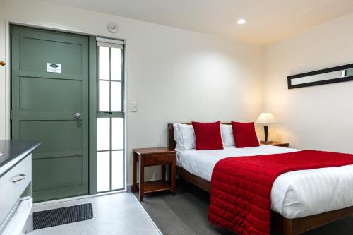 a bedroom with a bed and a red blanket at Jasmine Court Motel in Picton