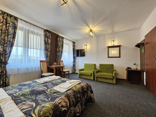 ヤスウォにあるRestauracja Hotel Imperialのベッドと緑の椅子が備わるホテルルームです。