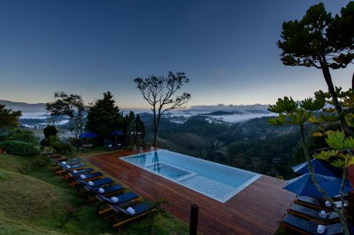 a pool with lounge chairs and a view of the mountains at Quinta dos Pinhais Pouso e Charme in Santo Antônio do Pinhal