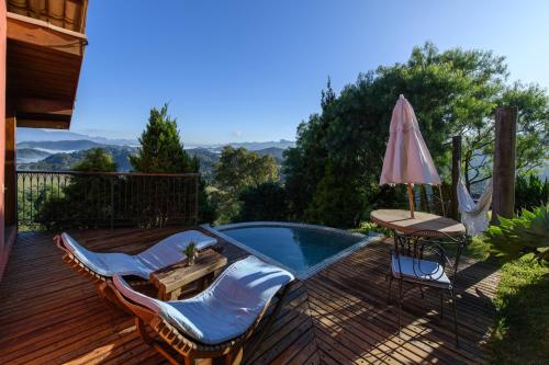 a deck with a pool and chairs and an umbrella at Quinta dos Pinhais Pouso e Charme in Santo Antônio do Pinhal