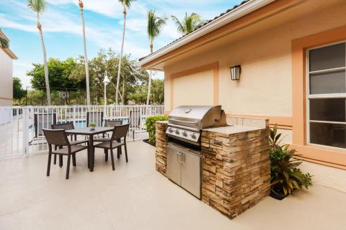 patio ze sprzętem do grillowania, stołem i krzesłami w obiekcie Residence Inn West Palm Beach w mieście West Palm Beach