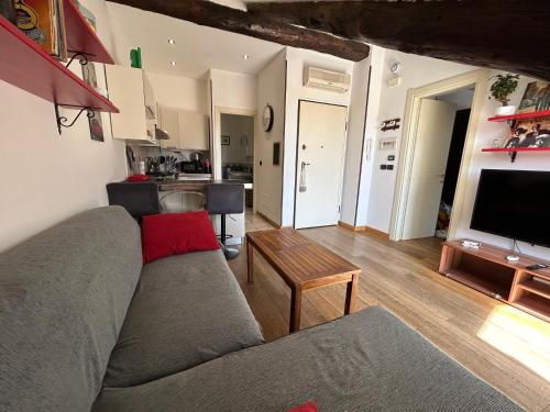 sala de estar con sofá gris y cocina en La Mansardina, en Turín