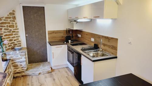 a small kitchen with white cabinets and a sink at KerLudi Le Ptit St Roch, gîte de charme 5km de la mer in Ploudalmézeau