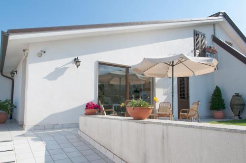 a white house with an umbrella and chairs at B&B Le Fresie in Nuoro