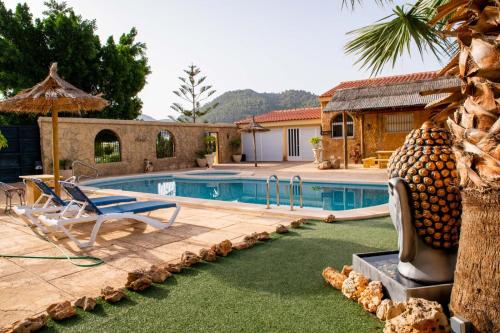 a pool with a palm tree and chairs and a house at Complejo rural los llanos in Mazarrón
