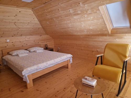 ein Schlafzimmer mit einem Bett und einem Stuhl in einer Hütte in der Unterkunft Vikendica Krlic in Mitrovac