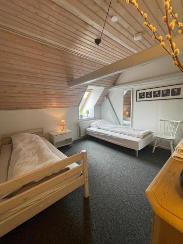 a bedroom with two beds in a room with wooden ceilings at Landligt ophold på Midtgård in Vamdrup