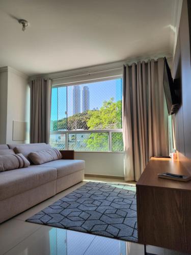 a living room with a couch and a large window at Apartamento Balneário Camboriú in Balneário Camboriú