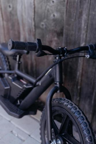 a black bike parked next to a wooden wall at Viesu nams “Kalna Raskumi” in Vecpiebalga