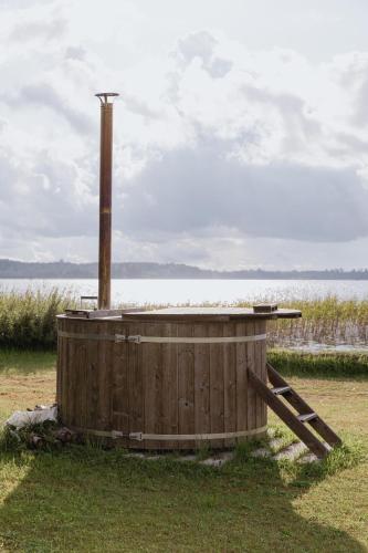 a wooden tub sitting in the grass next to a body of water at Viesu nams “Kalna Raskumi” in Vecpiebalga