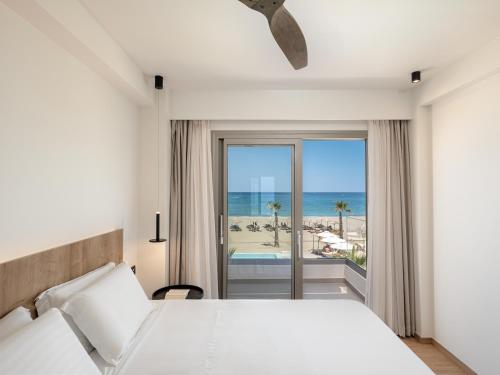 a bedroom with a bed and a view of the beach at Iperion Beach Hotel in Rethymno Town