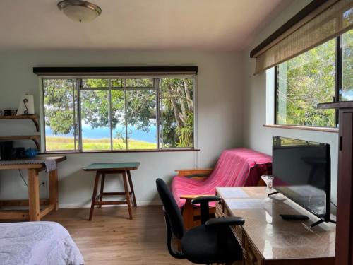 a room with a bed and a table and a tv at Waipio Studio Apartment in Kukuihaele