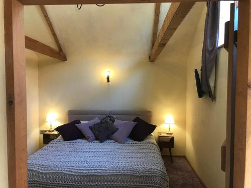 1 dormitorio con 1 cama con almohadas moradas y 2 lámparas en The Old Cow Shed en Thorndon