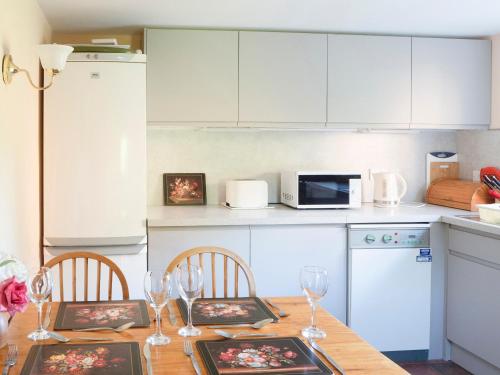 a kitchen with a wooden table with wine glasses at The Small Barn in Wood Norton