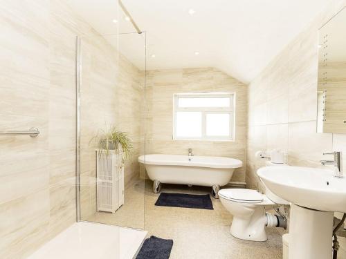 a bathroom with a tub and a toilet and a sink at Manor Farm in Coffinswell