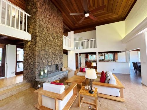 een open woonkamer met een stenen open haard bij Coral Hale 5br 3ba Luxury Home, AC, Hot Tub and Stunning Views in Princeville