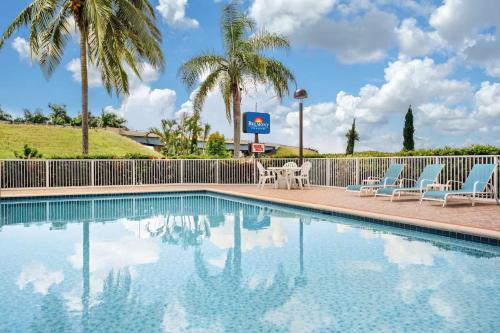 a swimming pool at a resort with chairs and palm trees at Belmont Inn & Suites in Florida City