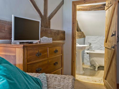 a bathroom with a television on a dresser with a tub at Lavender Cottage - Uk4061 in Buxton