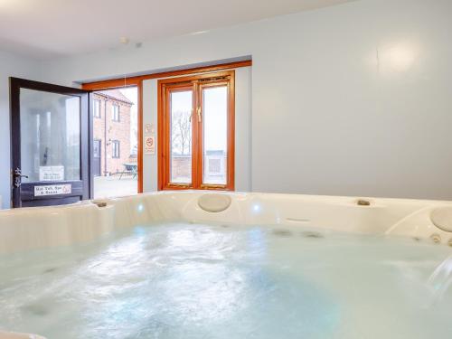 a bath tub filled with water in a room at Lintel Barn - E5253 in Runcton Holme