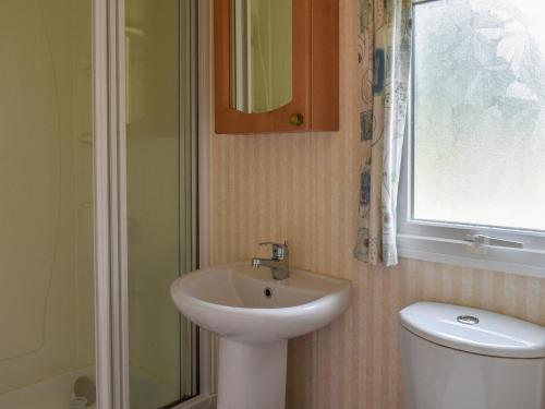a bathroom with a sink and a toilet and a window at Spinney Retreat in East Wellow