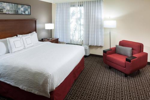um quarto de hotel com uma cama e uma cadeira vermelha em TownePlace Suites by Marriott San Antonio Airport em San Antonio