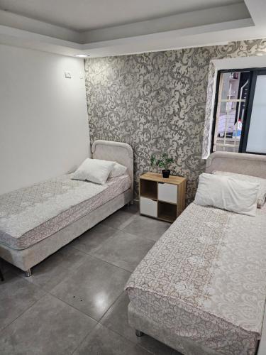 a bedroom with two beds and a table and a window at laila's boutique apartment in Haifa