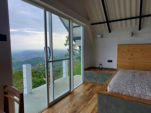 a bedroom with a bed and a large glass window at Flow Nature Cottage in Beragala