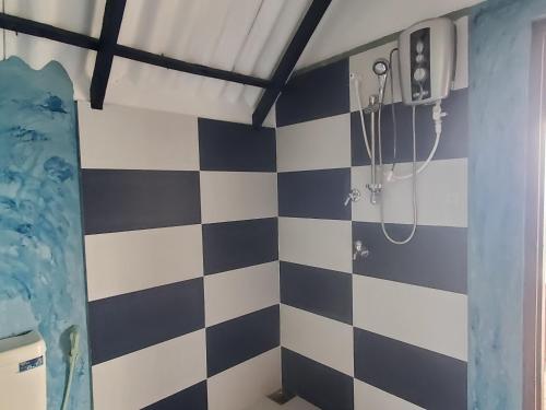 a bathroom with a black and white checkered wall at Flow Nature Cottage in Beragala