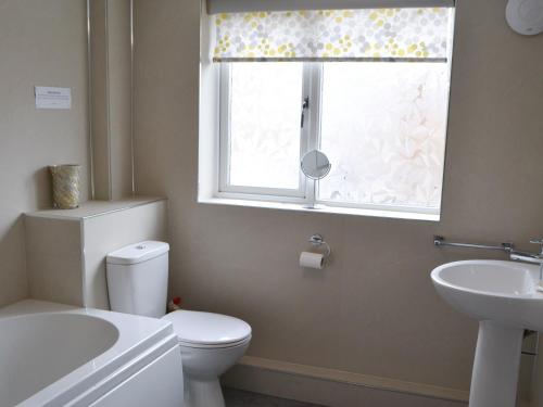 a bathroom with a toilet and a sink and a window at Kittiwakes in Amble
