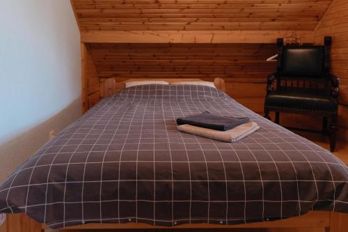 a bed with a blanket and a chair in a room at Viesu nams “Kalna Raskumi” in Vecpiebalga