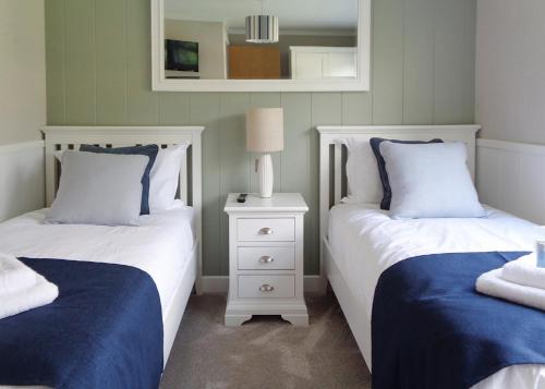 a bedroom with two beds with blue and white sheets at Otters Mead Boutique Lodges in Beetley