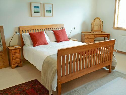 um quarto com uma cama de madeira e almofadas vermelhas em Fairfield em Ackergill