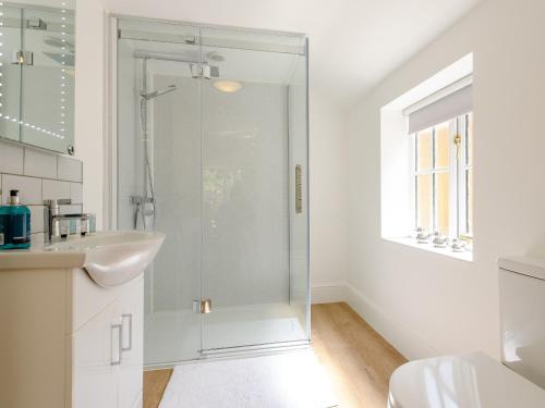 a white bathroom with a shower and a sink at The Chicken Coop in Fulletby