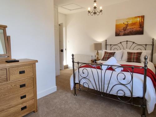 um quarto com uma cama, uma cómoda e um espelho em Karslake Cottage em Winsford