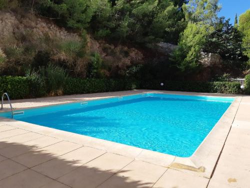 una piscina con acqua blu in un cortile di T2 vue panoramique, piscine, parking, wifi, 2 tv connectées, netflix, clim, ascenseur, salon de jardin teck, barbecue a Sète