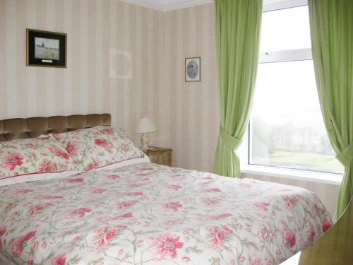 a bedroom with a bed with a floral bedspread and a window at Alondra Cottage in Barrowford