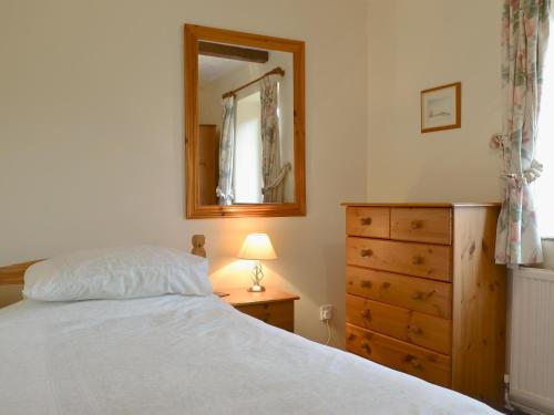 a bedroom with a bed and a dresser and a mirror at Stable Cottage 4 - Ukc3743 in Bawdeswell