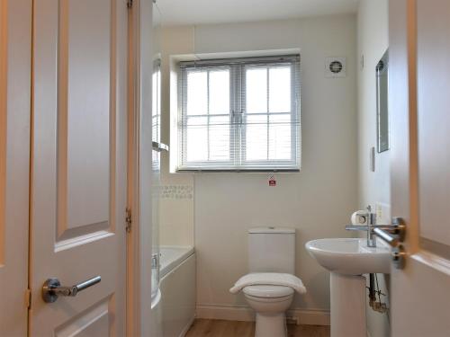 a bathroom with a toilet and a sink and a window at Perran Cottage in Reighton