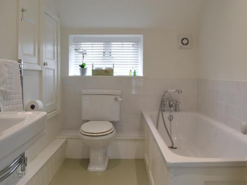 a bathroom with a toilet and a tub and a sink at Sunny Cottage in Bulmer
