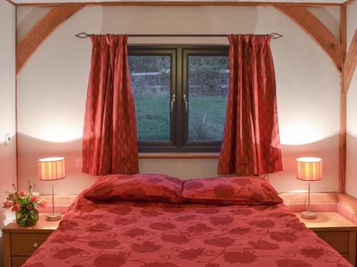Ashburnham的住宿－Boreham Bridge Barn，一间卧室配有一张带两盏灯的床和一扇窗户。