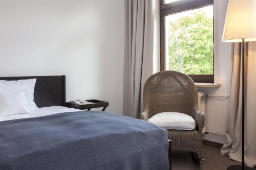 a bedroom with a bed and a chair and a window at Hotel Dieksee - Collection by Ligula in Malente