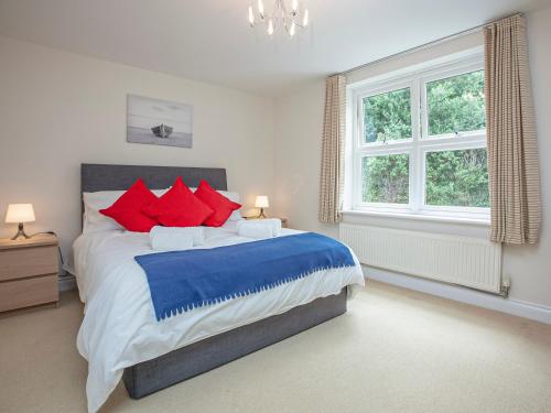a bedroom with a large bed with red and blue pillows at Waves - Great Cliff in Dawlish