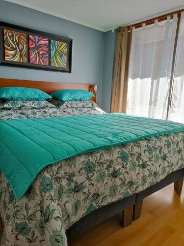 a bed with a green comforter and a window at Bellavista Dardignac 28 in Santiago