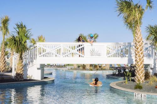 a woman riding a surfboard under a bridge in the water at Golf Course Living at Palmilla Beach in Port Aransas