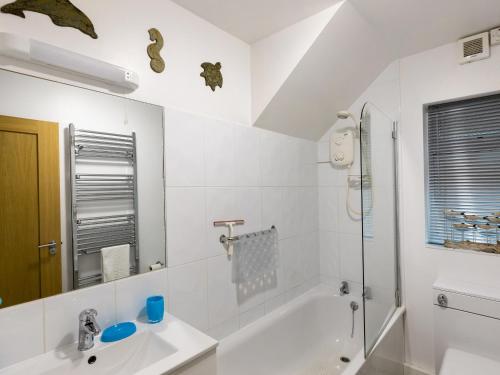 a white bathroom with a sink and a bath tub at Rockvale 1 in Salcombe