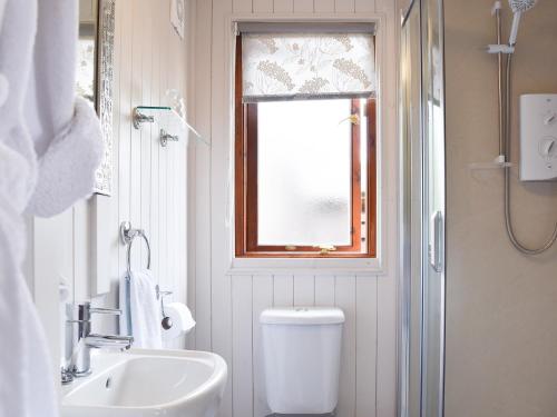 a bathroom with a toilet and a sink and a window at Lakeside Cabin in Kingston Blount