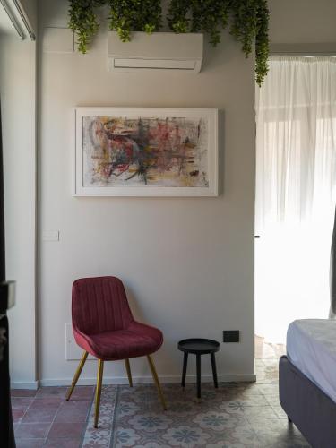 a bedroom with a red chair and a table at VICOLO SAN GAETANO -luxury rooms- in Catania